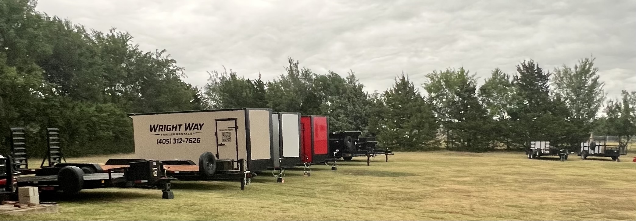 Panoramic view of WrightWay Trailer Rentals fleet lineup including enclosed dump and utility trailers